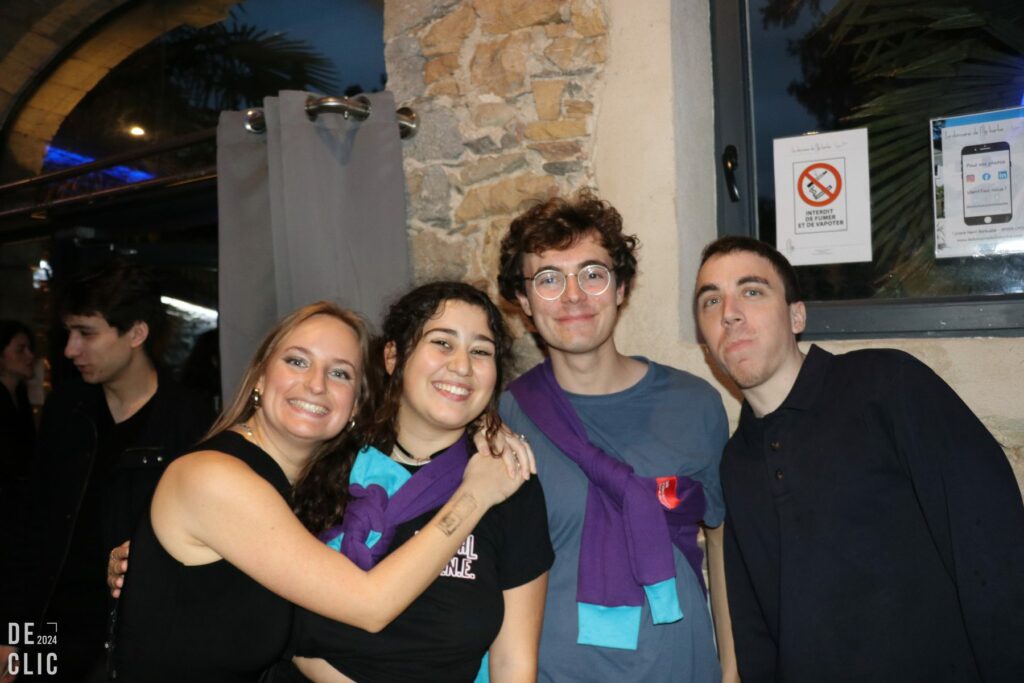 Quatre étudiants souriants posent serrés les uns contre les autres devant un mur de pierre, à l'entrée du musée.