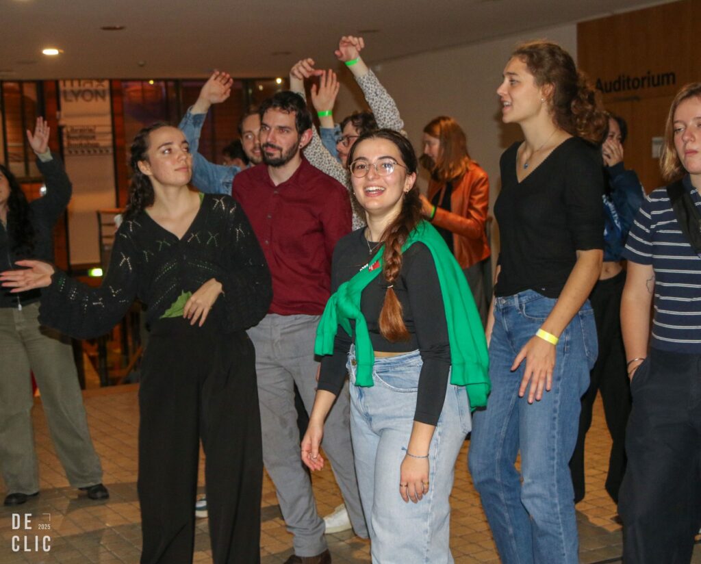 Un groupe d'étudiants danse les bras levés devant l'entrée de l'auditorium du musée.